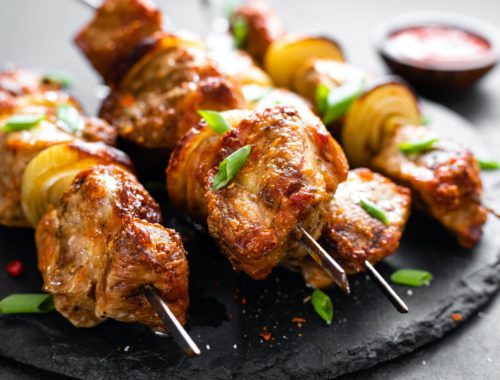 Grilled meat skewers, shish kebab on black background