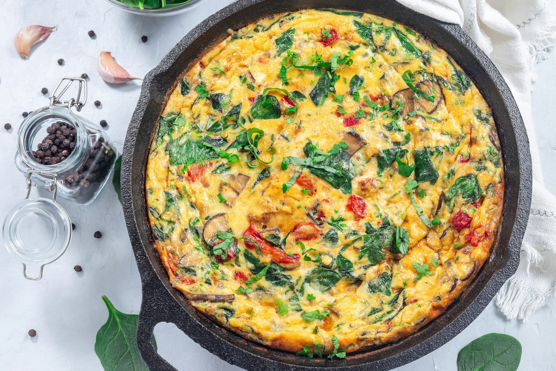 Brunch egg frittata with spinach, roasted red peppers, mushrooms, in cast iron, horizontal, top view